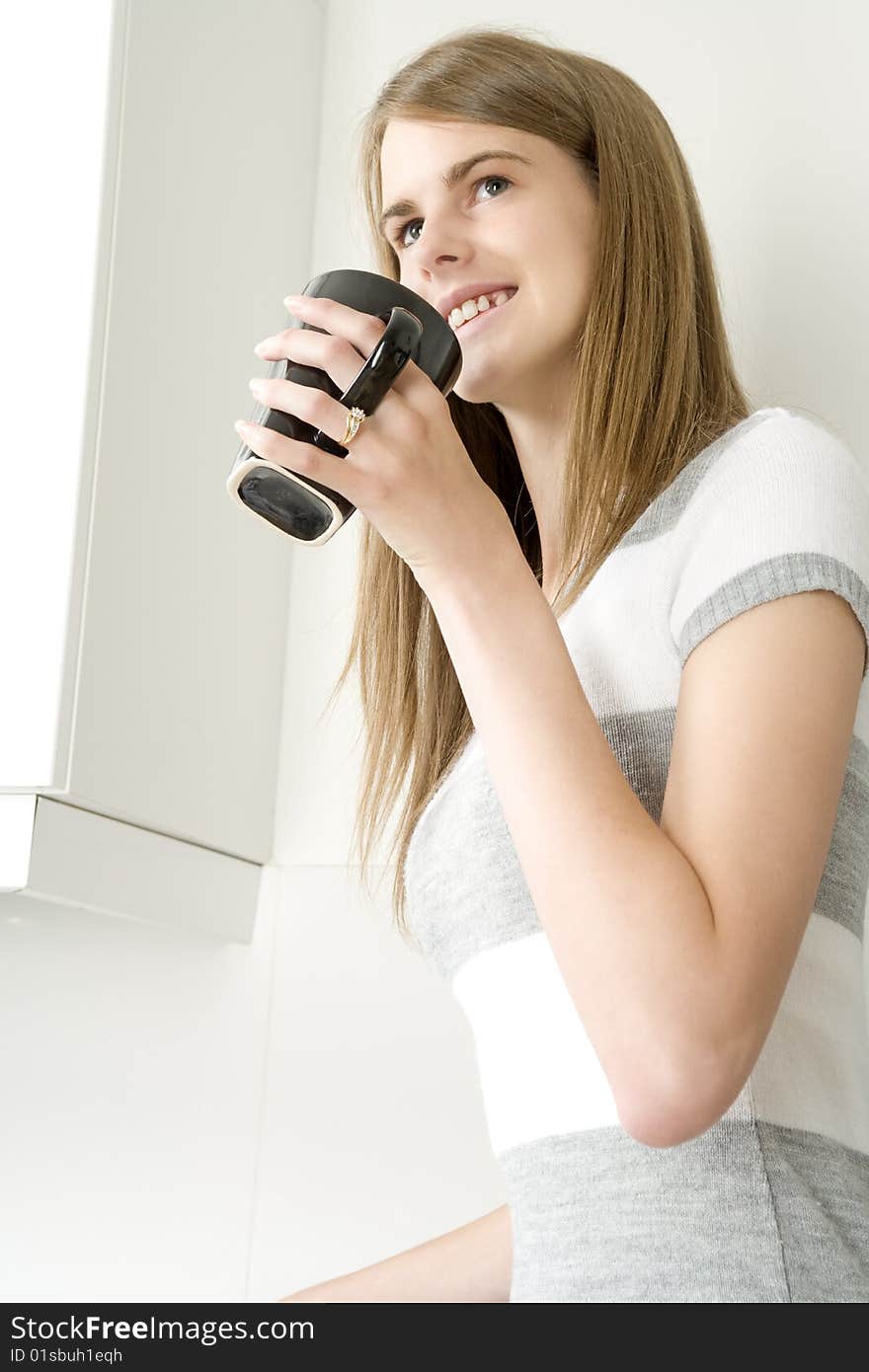 Female model with hot drink in kitchen setting. Female model with hot drink in kitchen setting