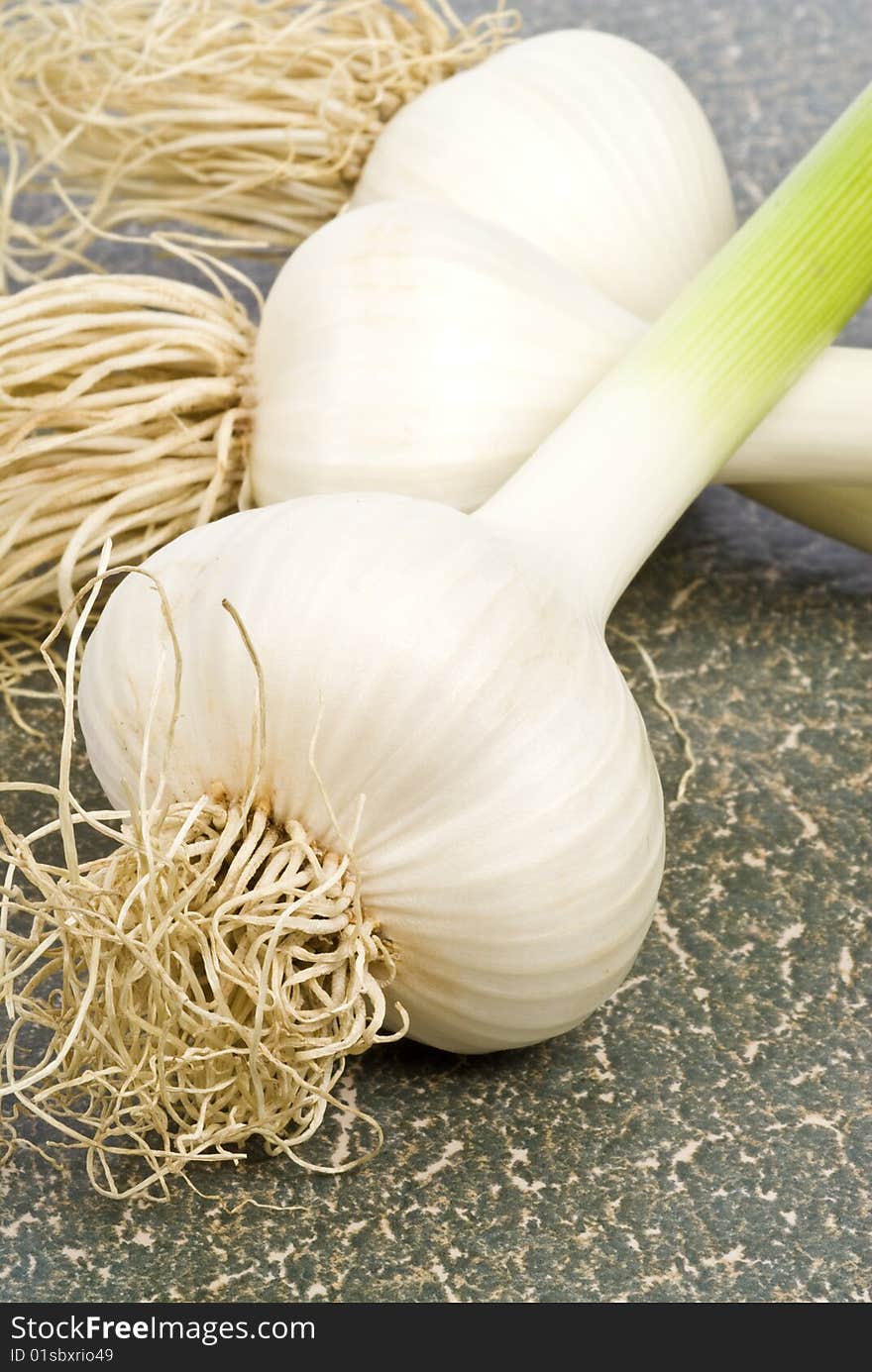 Close-up of three bulbs of fresh garlic on a textured surface. Close-up of three bulbs of fresh garlic on a textured surface.