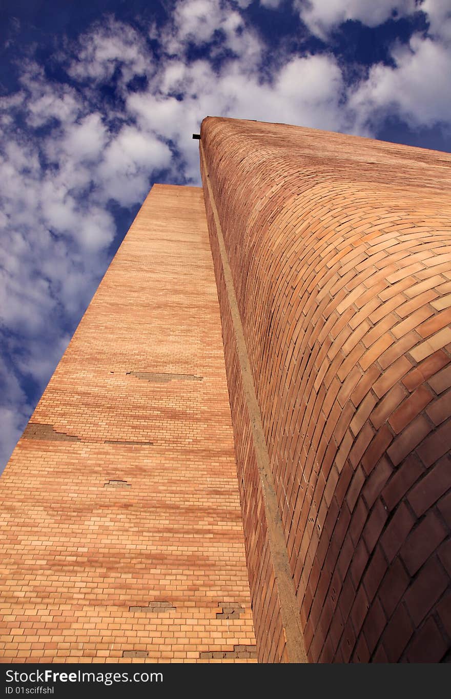 High brick building against the blue sky and clouds