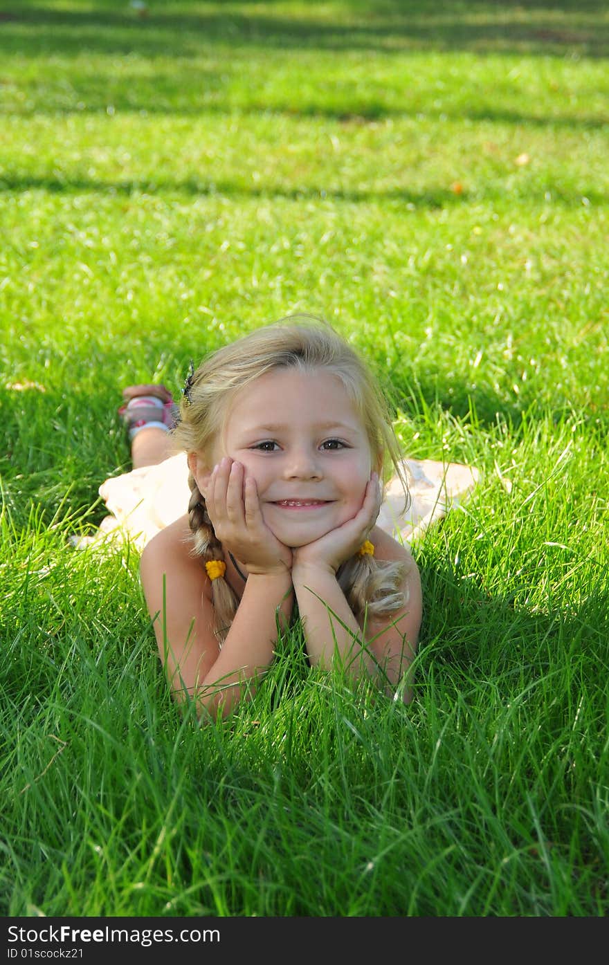 Little girl lays on a grass