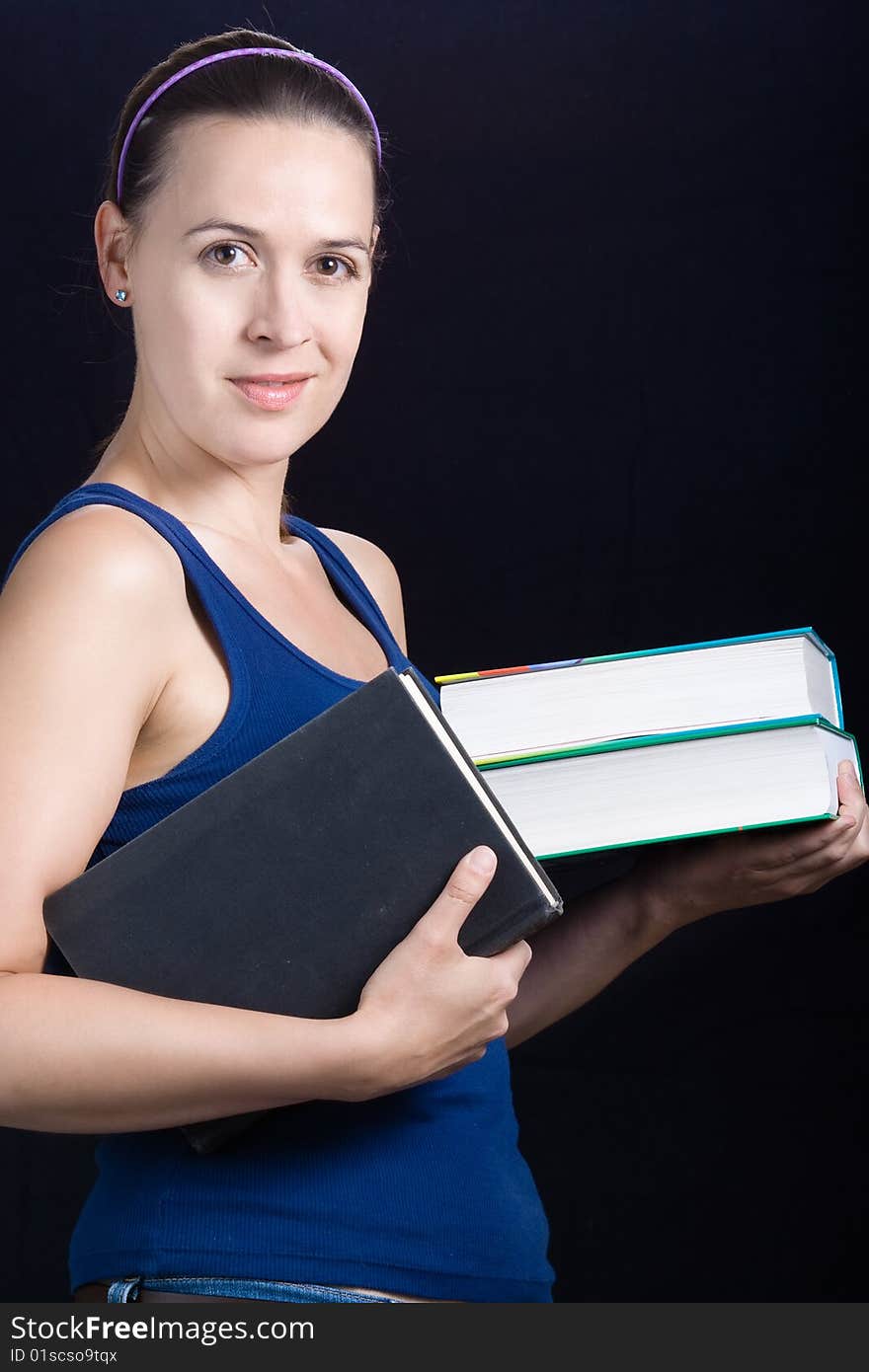 A young woman with books on a dark background. A young woman with books on a dark background.