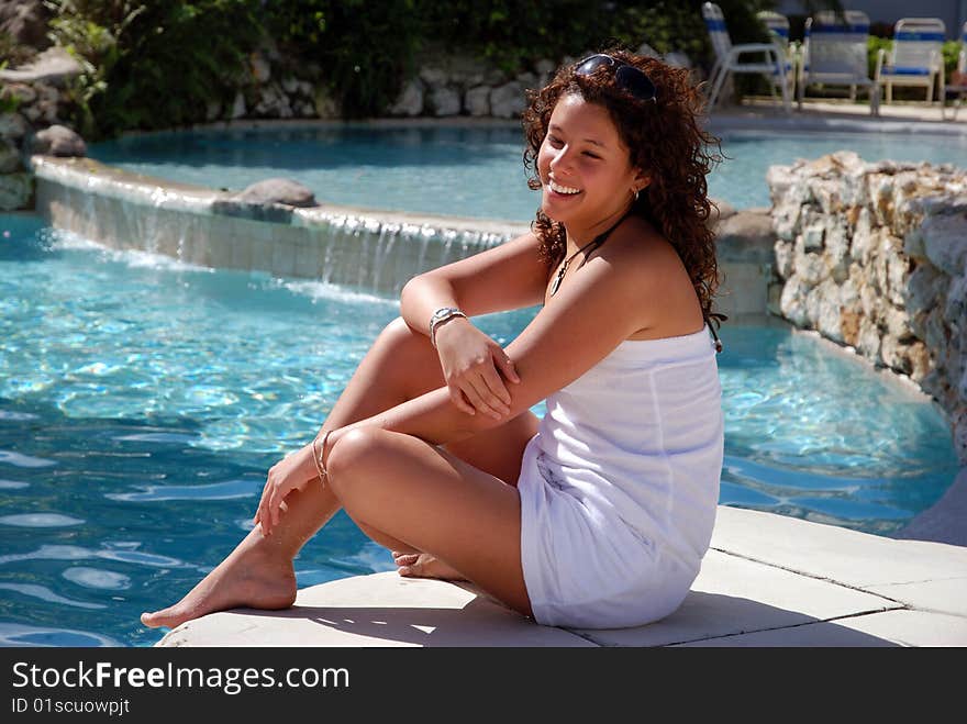 Laughing girl sitting by the pool in Grand Cayman island resort (Cayman Islands).