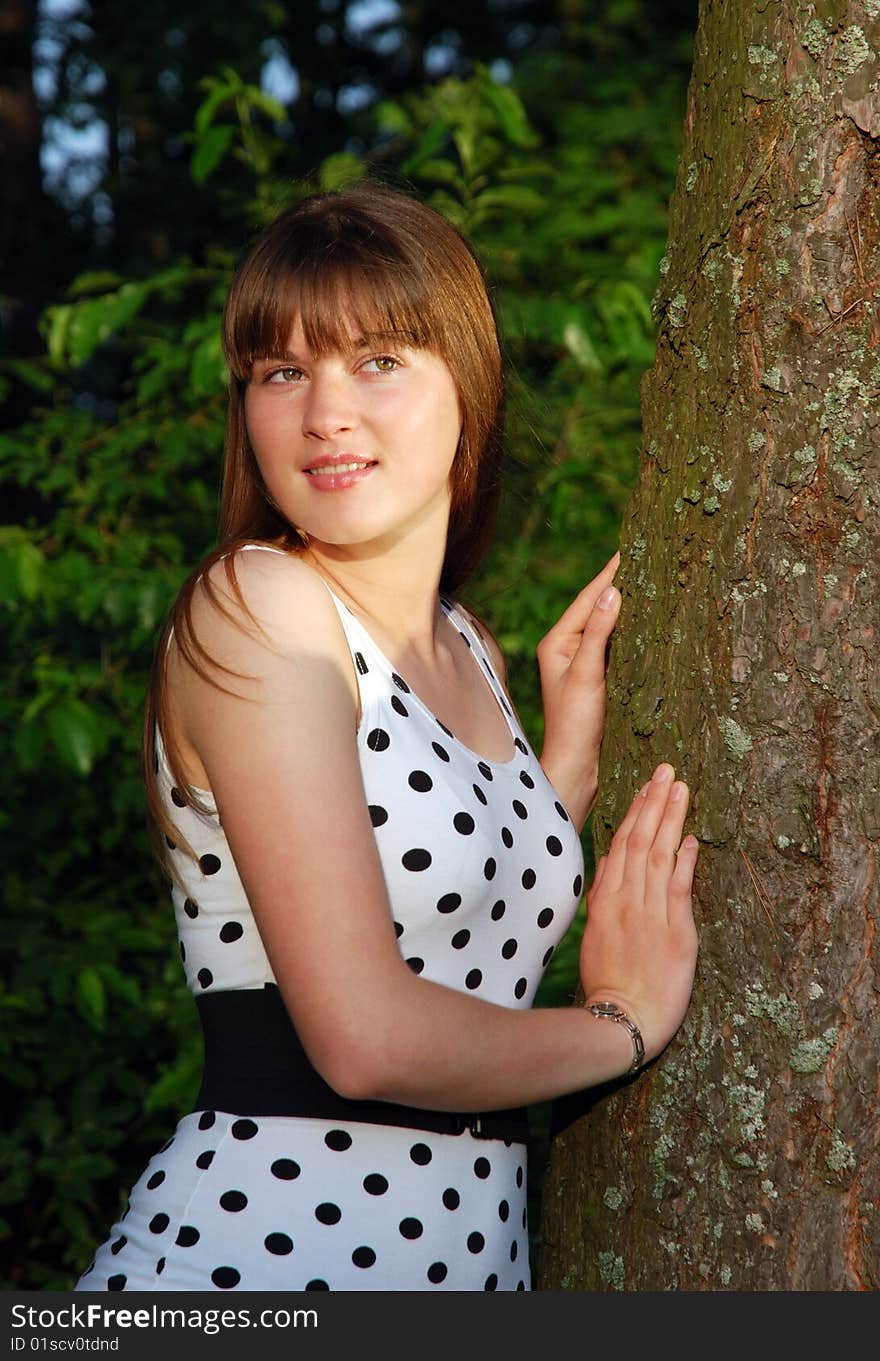 The portrait of a girl standing by the tree. The portrait of a girl standing by the tree.