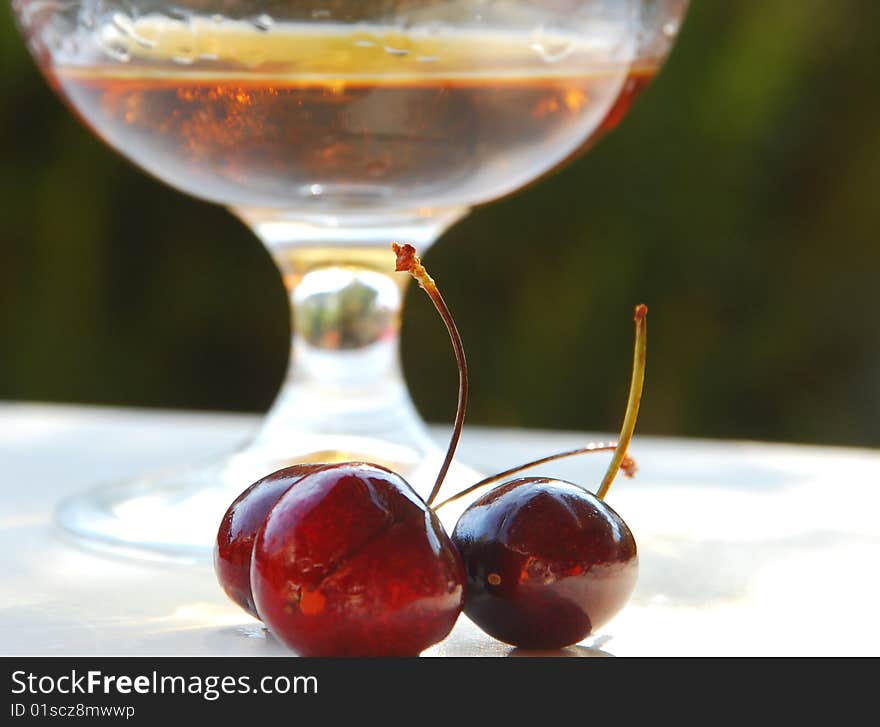 Cherries in front of a glass of liquere