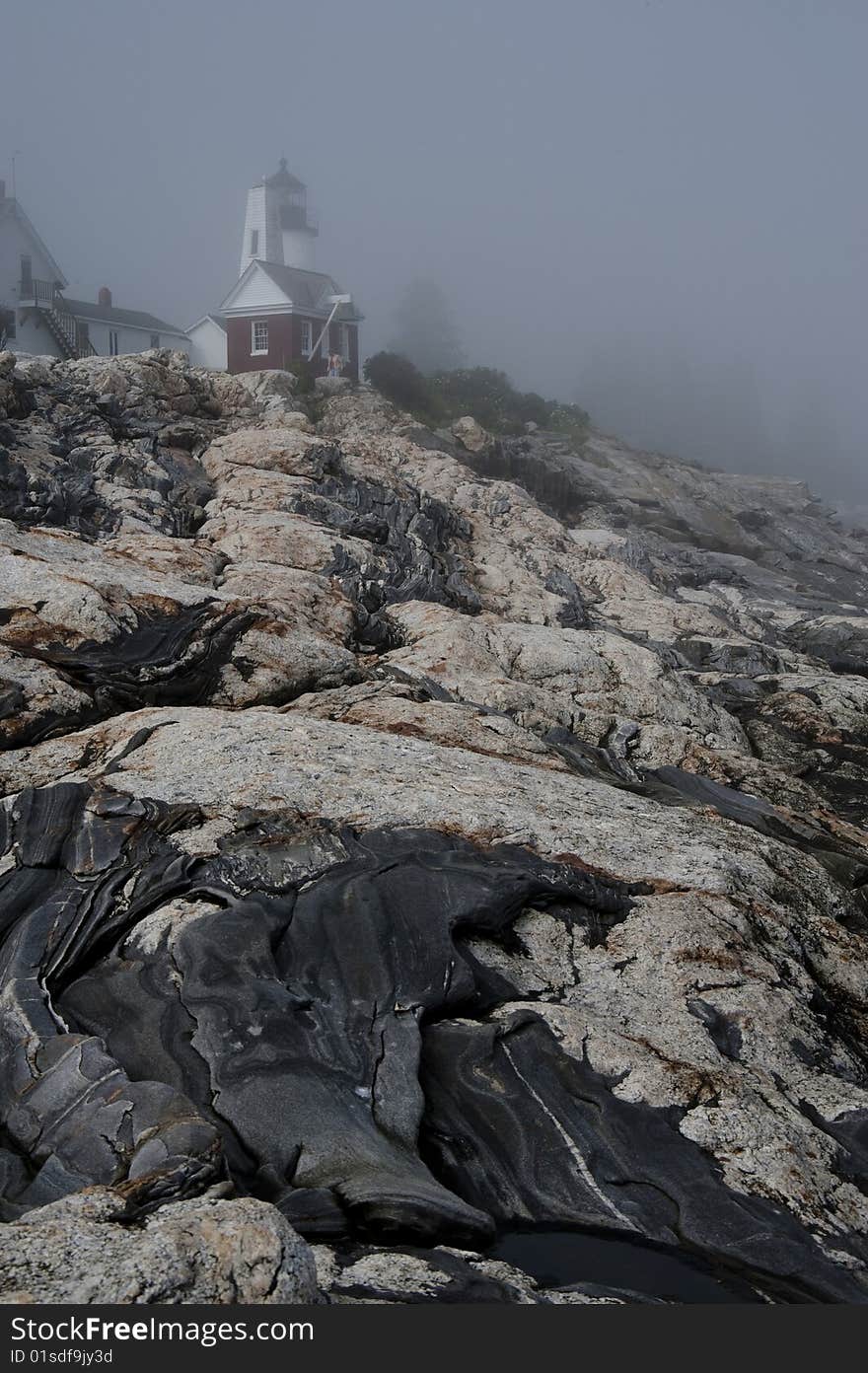 A lighthouse stands tall in morning fog. A lighthouse stands tall in morning fog.