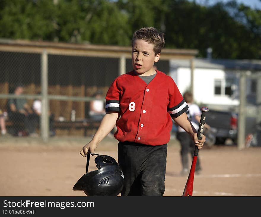 This young boy just struck out and you can see by his facial expression that he is not very happy about that. This young boy just struck out and you can see by his facial expression that he is not very happy about that.