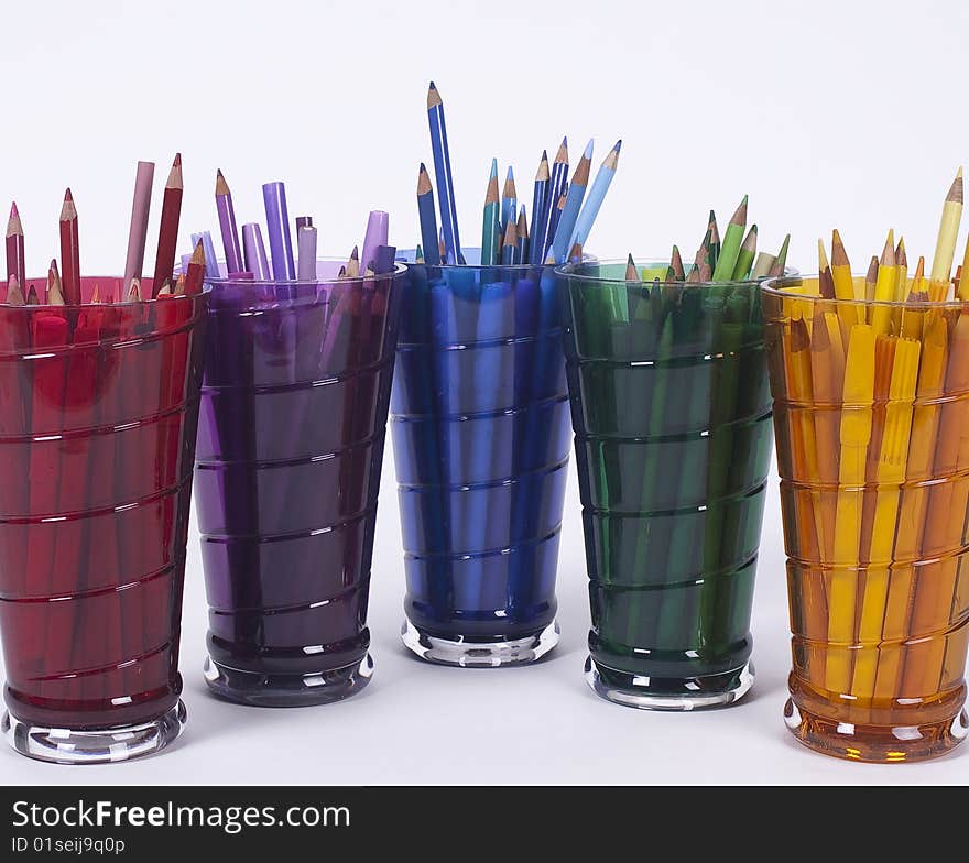 Five drinking glass holding colored drawing pencils and pens. Five drinking glass holding colored drawing pencils and pens.