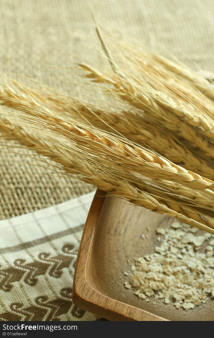 Wheat ears and wooden bowl on sacking. Food background.