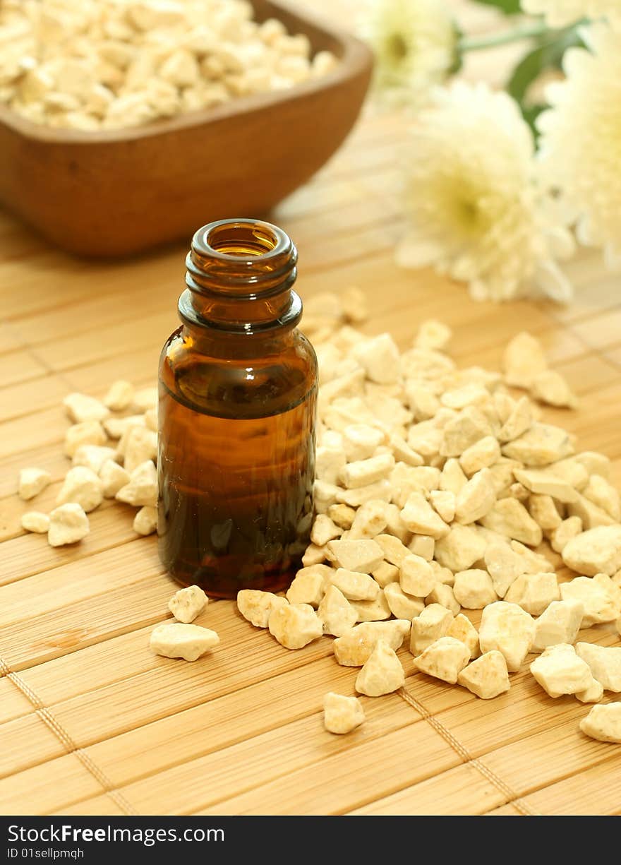 Bottle of essence oil with flowers and stones. Spa concept.