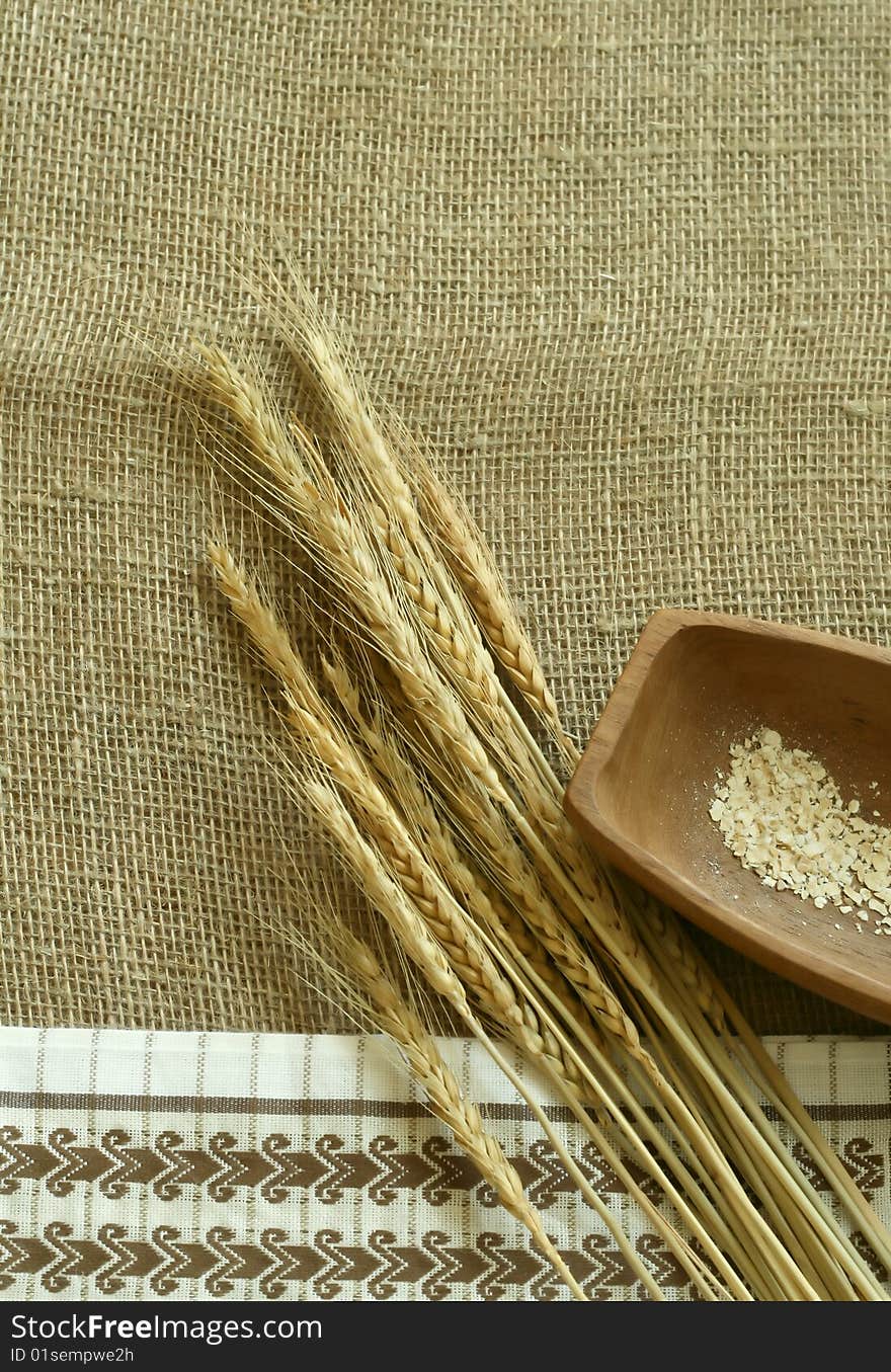 wheat ears, wooden bowl and   kitchen towel on sacking. wheat ears, wooden bowl and   kitchen towel on sacking