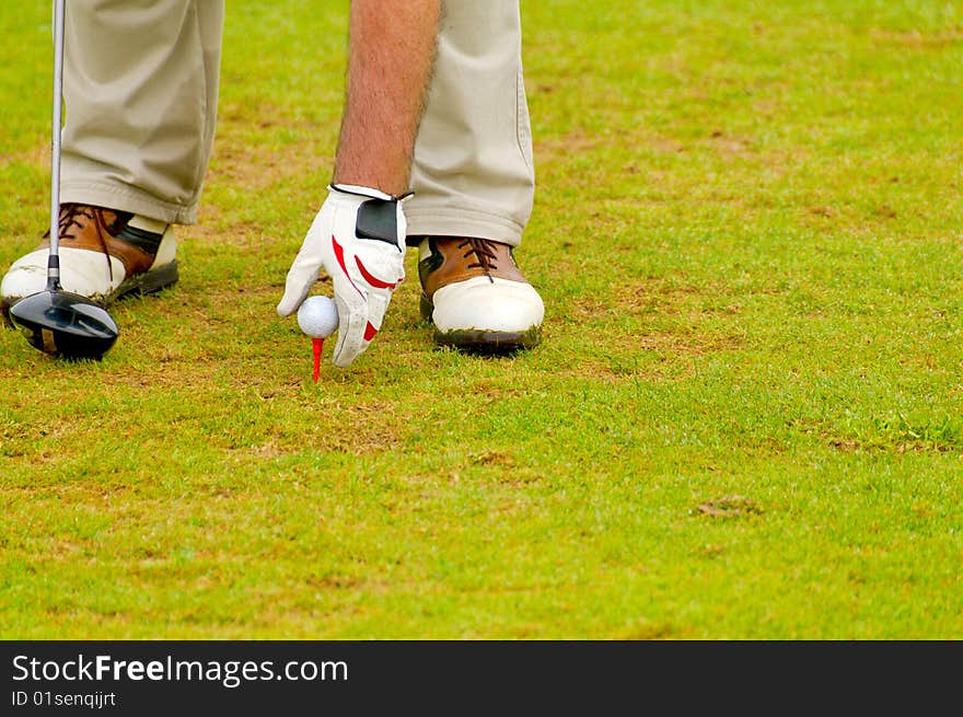 A senior player put a ball on a tee. A senior player put a ball on a tee