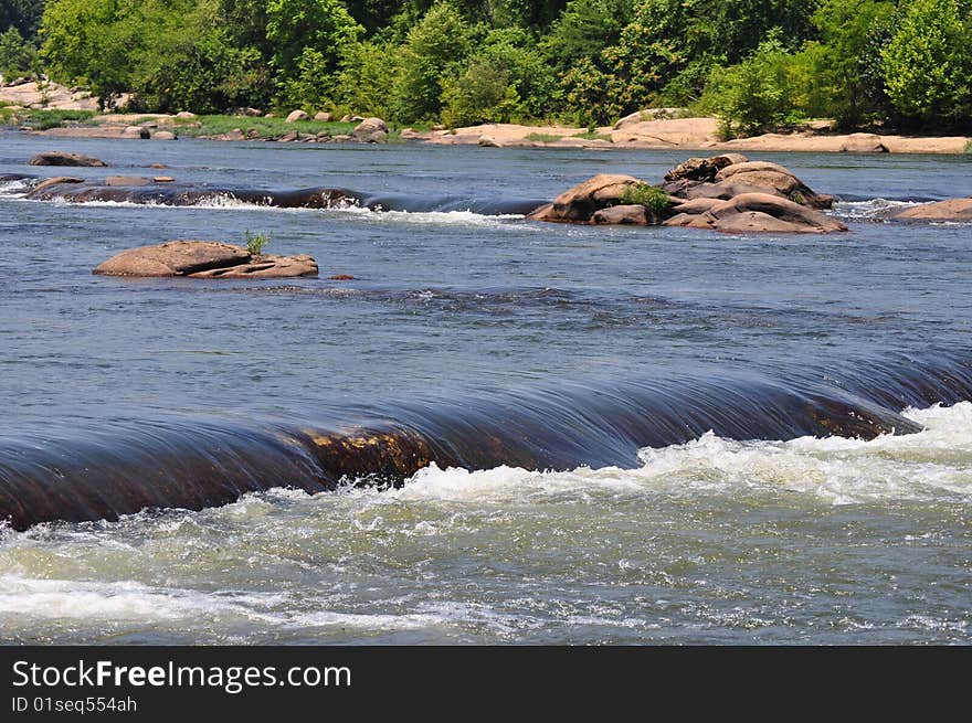 A small waterfall runs over the rocks at the river. A small waterfall runs over the rocks at the river.