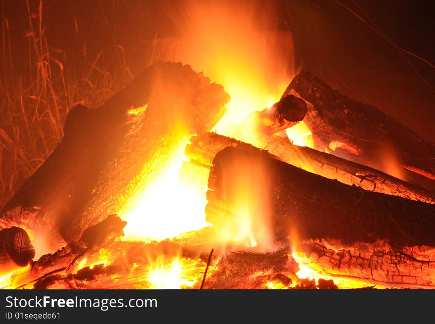 Logs stack up to burn in a hot orange fire. Logs stack up to burn in a hot orange fire.