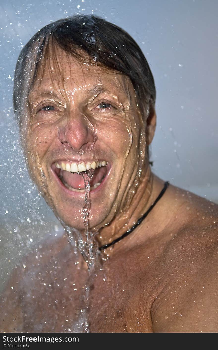 A colour portrait of a happy laughing forties man under a shower outside. A colour portrait of a happy laughing forties man under a shower outside.