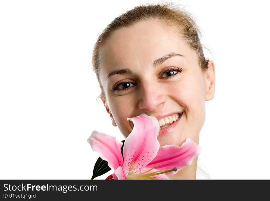 A smiling nice blond girl posing with a pink lily near her face on a white background. A smiling nice blond girl posing with a pink lily near her face on a white background