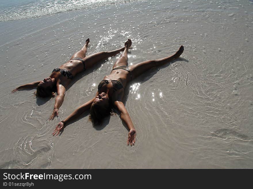 Two sweet teenage girls lying on the beach