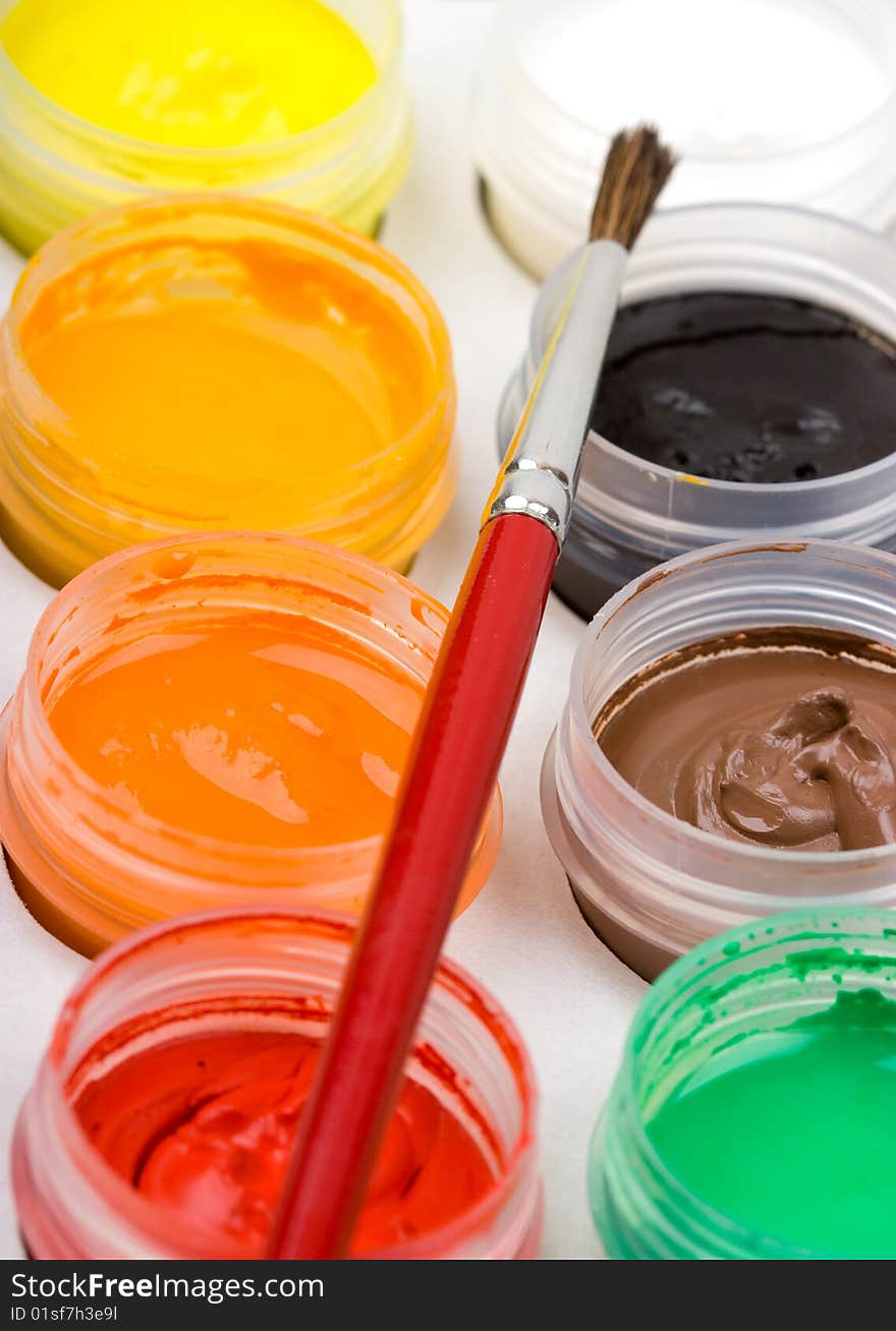 Group of colorful paint cans with brush to background