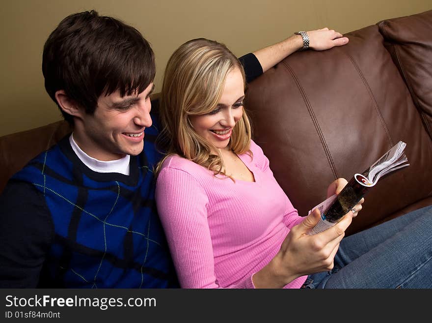 A happy couple reads on the couch. A happy couple reads on the couch