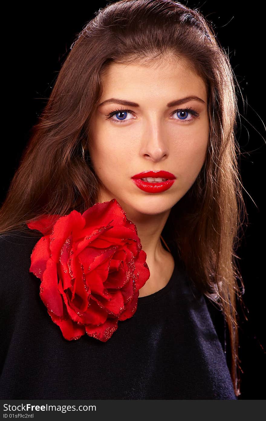 Portrait of a young beautiful brunettes with red lips in a black blouse decorated with a rose. Portrait of a young beautiful brunettes with red lips in a black blouse decorated with a rose