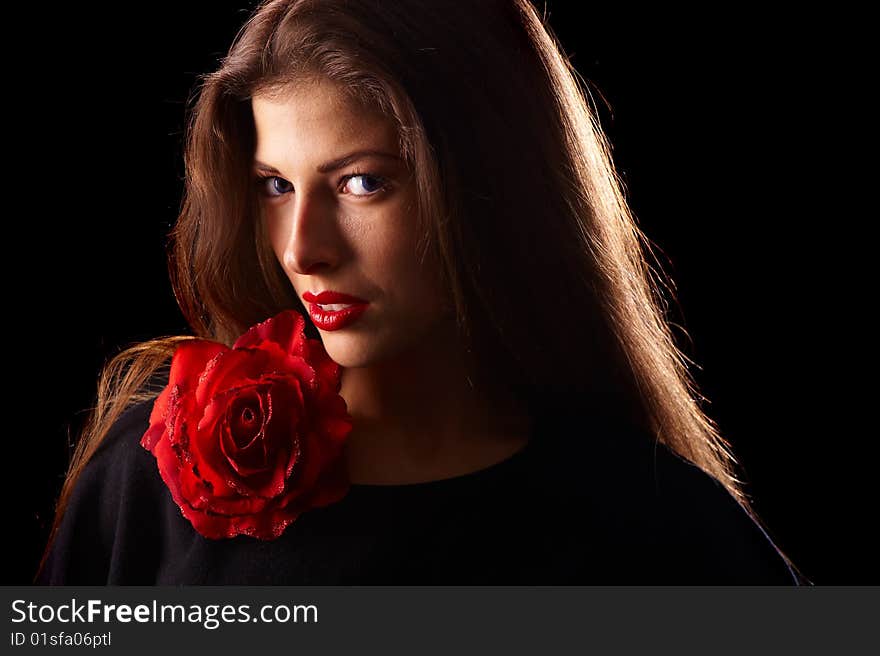 Portrait of a young beautiful brunettes with red lips in a black blouse decorated with a rose. Portrait of a young beautiful brunettes with red lips in a black blouse decorated with a rose