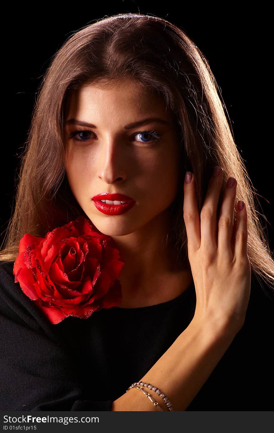 Portrait of a young beautiful brunettes with red lips in a black blouse decorated with a rose. Portrait of a young beautiful brunettes with red lips in a black blouse decorated with a rose