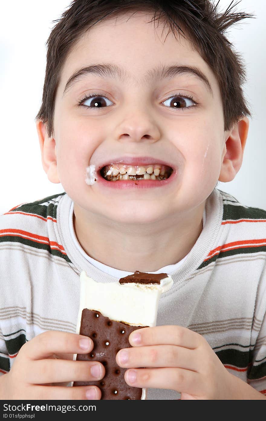 Adorable happy six year old boy eating icecream sandwiches. Adorable happy six year old boy eating icecream sandwiches.