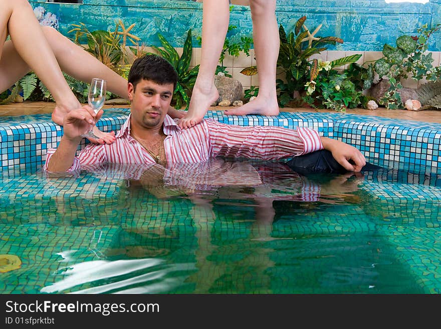 Handsome young man in a pool surrounded by women's feet. Handsome young man in a pool surrounded by women's feet