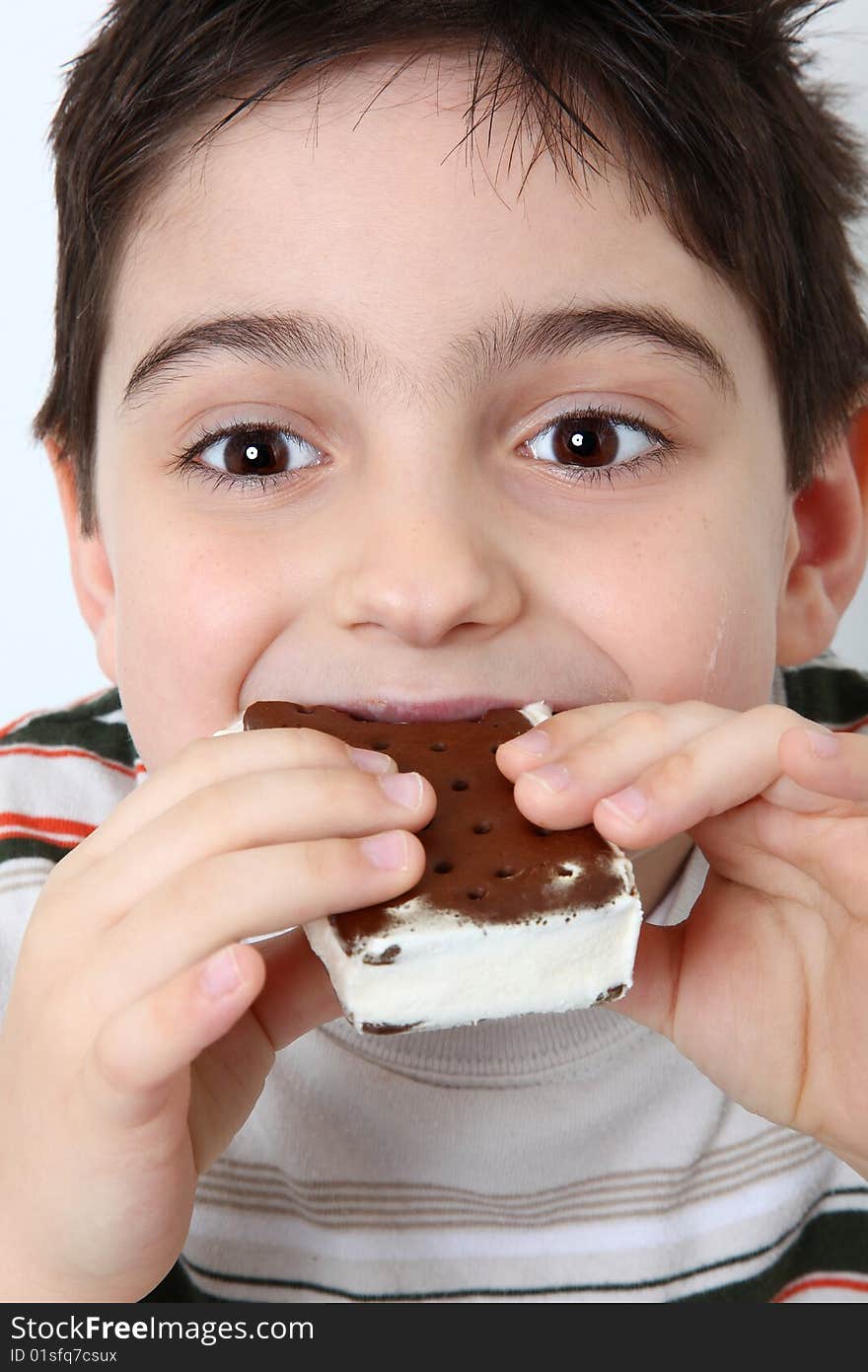 Adorable six year old boy eating icecream sandwich. Adorable six year old boy eating icecream sandwich.