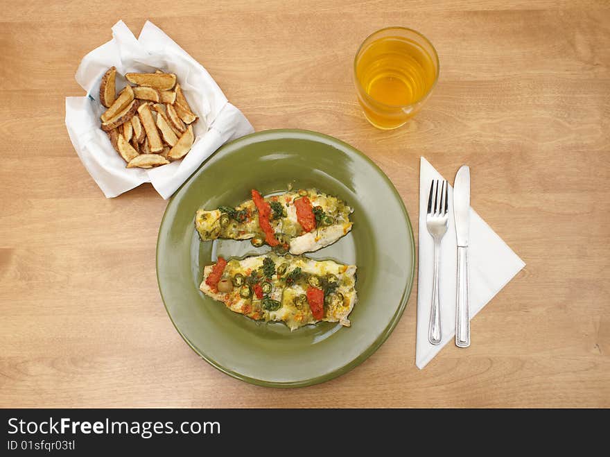 A plate of fresh fish with many seasonings, alongside a bowl of fresh cut frenchfries. A plate of fresh fish with many seasonings, alongside a bowl of fresh cut frenchfries.