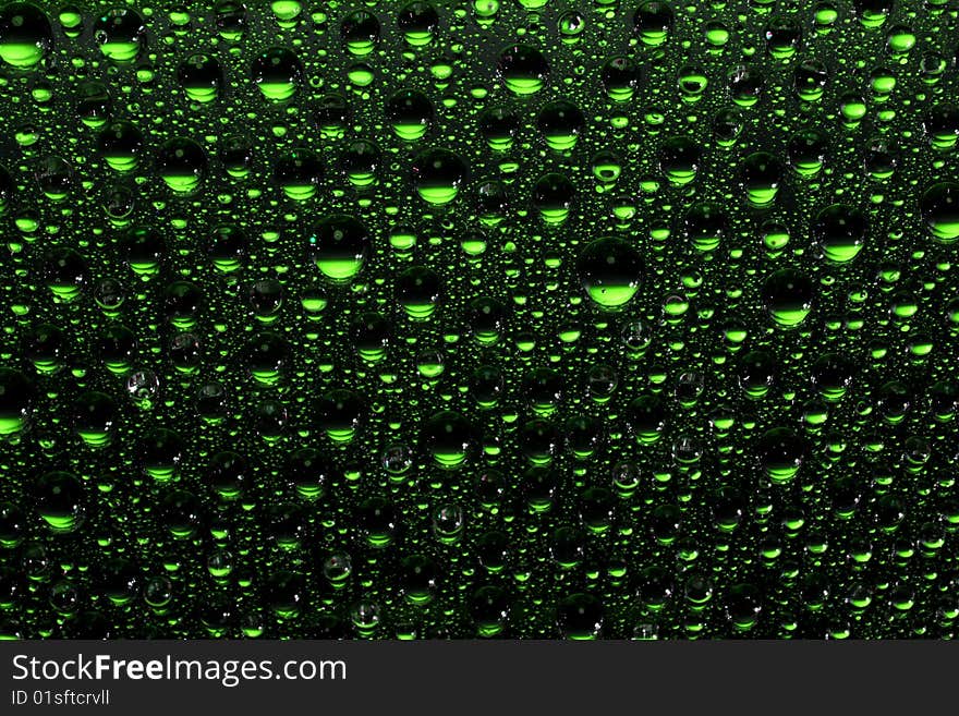 Green water drops against black background