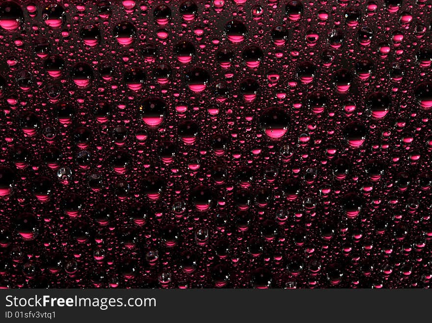 Pink water drops against black background