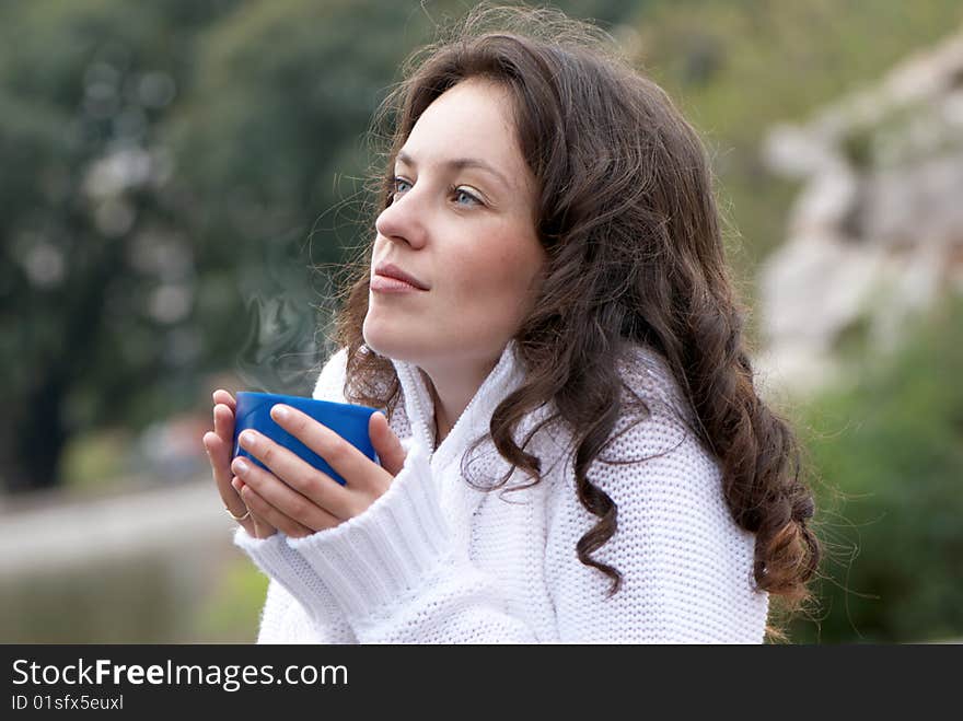 Portrait of the young woman a mug of a hot drink outdoors. Portrait of the young woman a mug of a hot drink outdoors