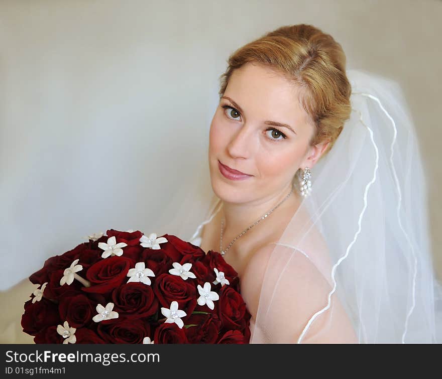 Portrait of a bride with bouquet of red roses with intentionally left copy-space on left side.