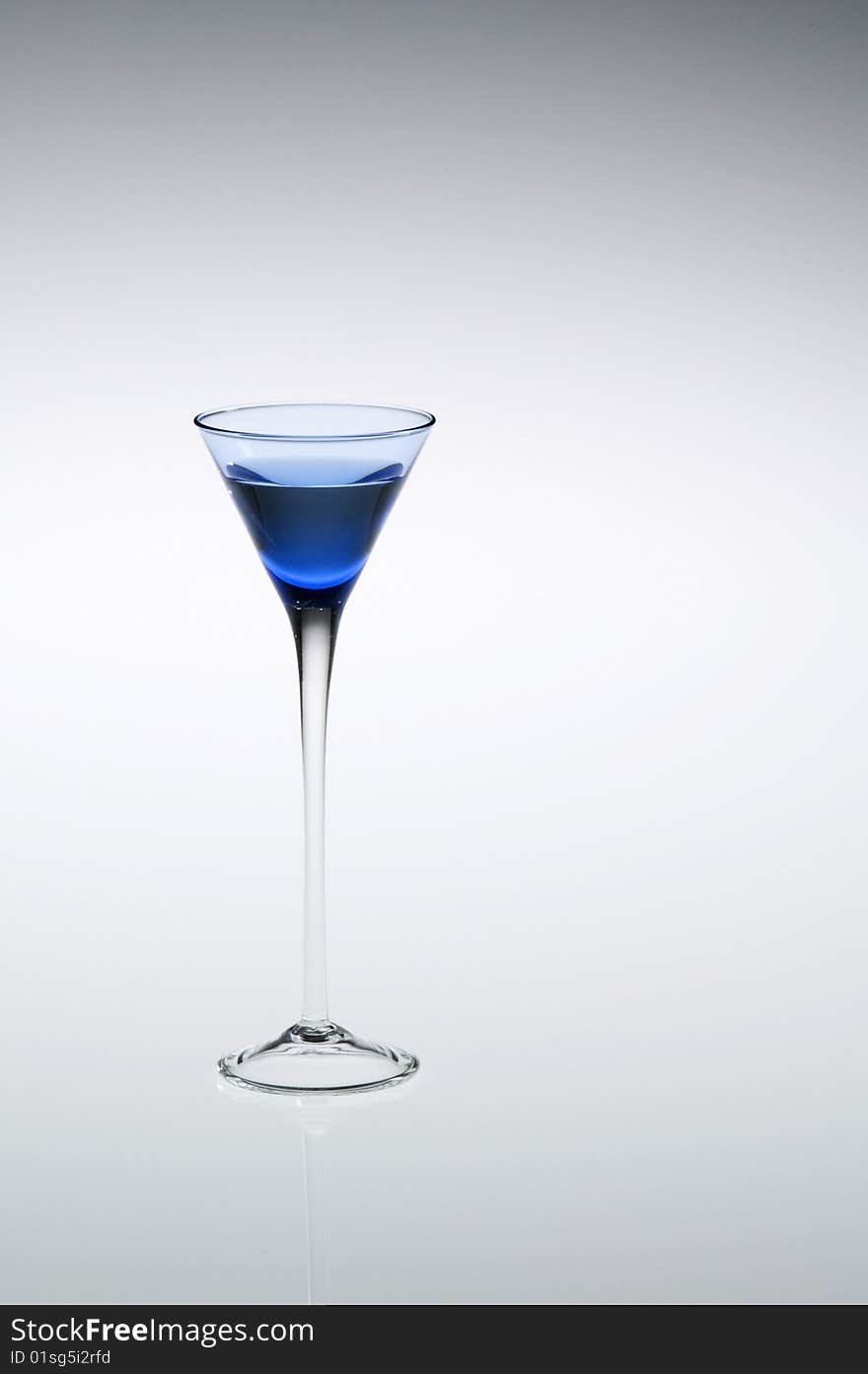 Blue cordial, aperitif, or liqueur glass with stem reflecting, off-center to left of frame. Blue cordial, aperitif, or liqueur glass with stem reflecting, off-center to left of frame.