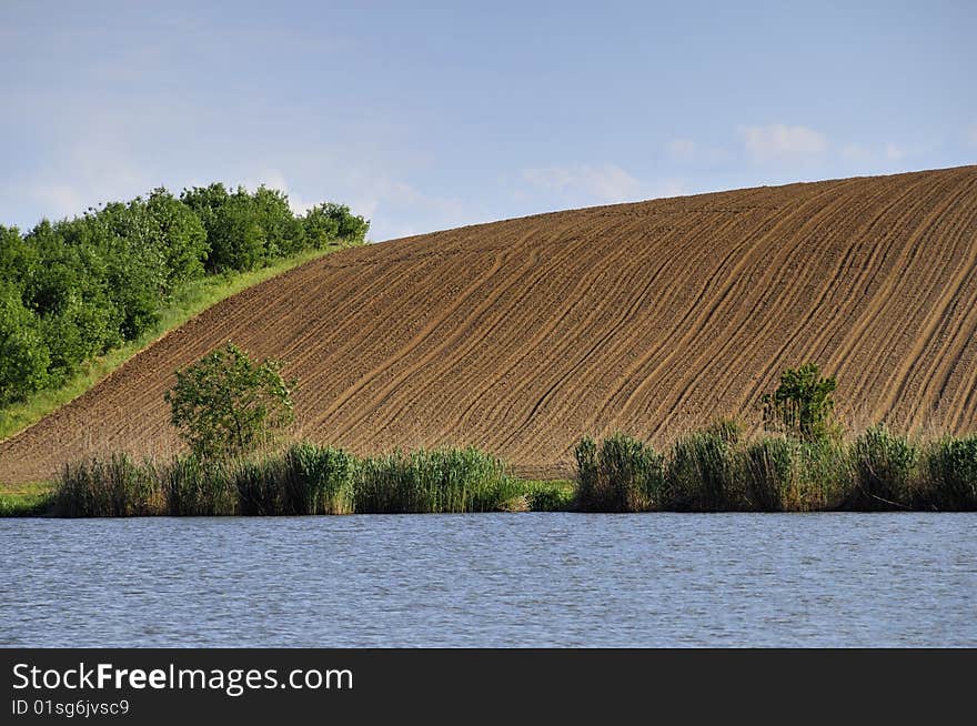 View on the field on a hill by the lake. View on the field on a hill by the lake