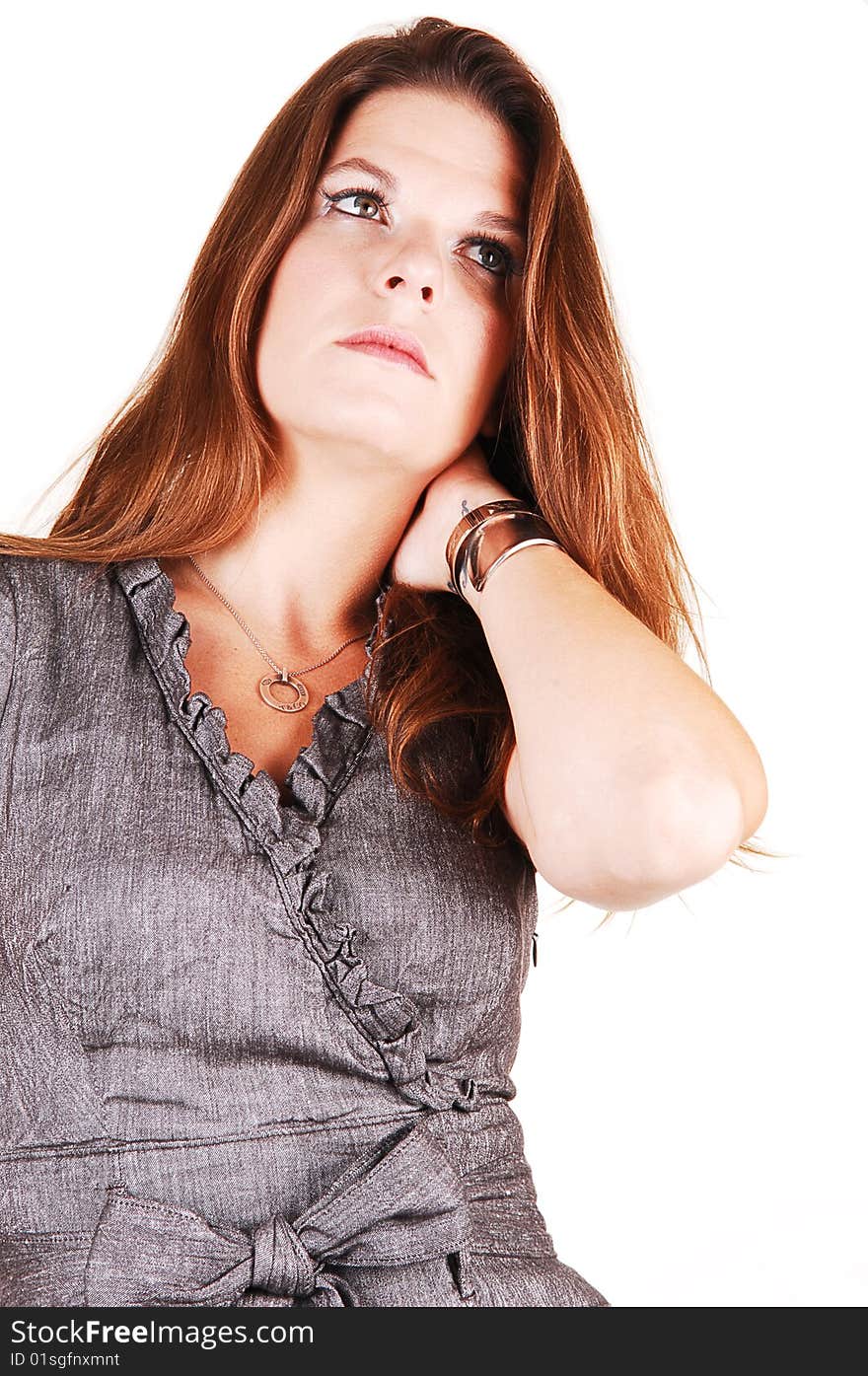 Young light red haired woman in an gray dress standing in the studio 
for white background, has her left hand on the neck under the hair. Young light red haired woman in an gray dress standing in the studio 
for white background, has her left hand on the neck under the hair.