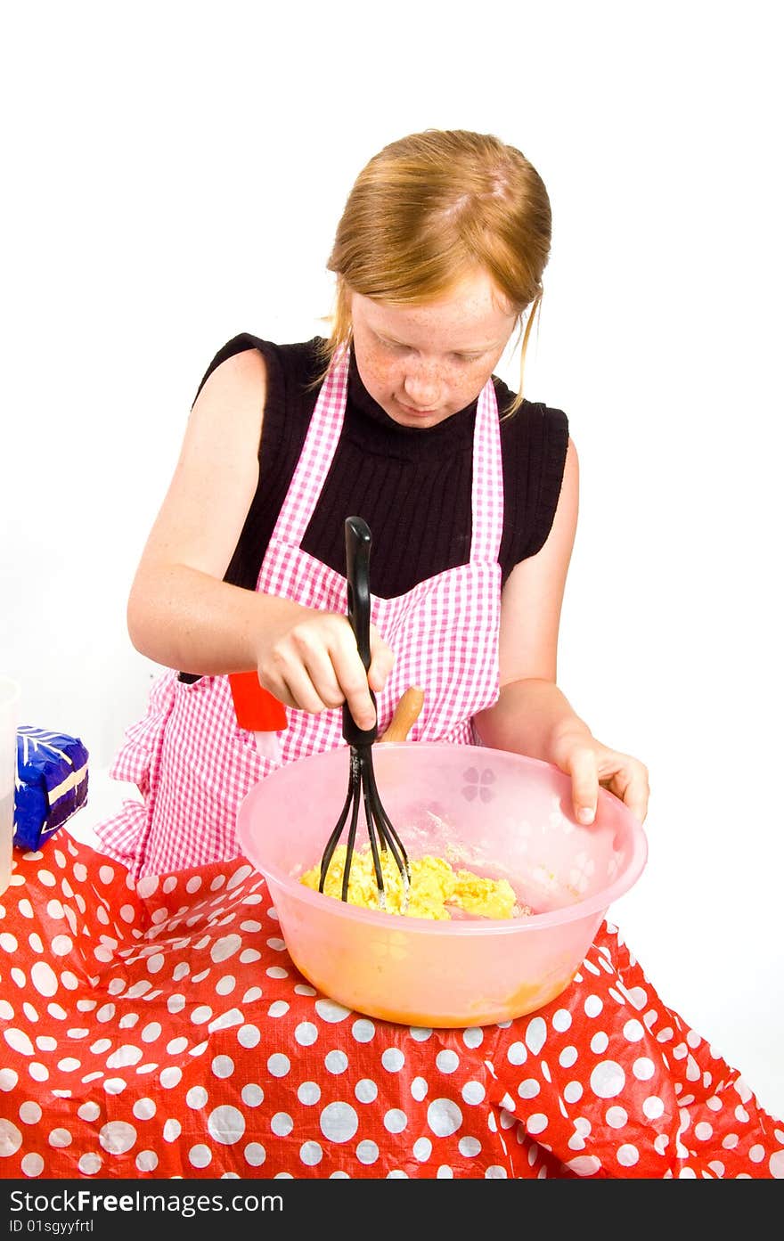 Redhead girl is making pancake dough isolated on white