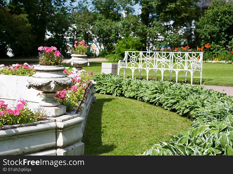 Flower-bed in a summer garden with a bench