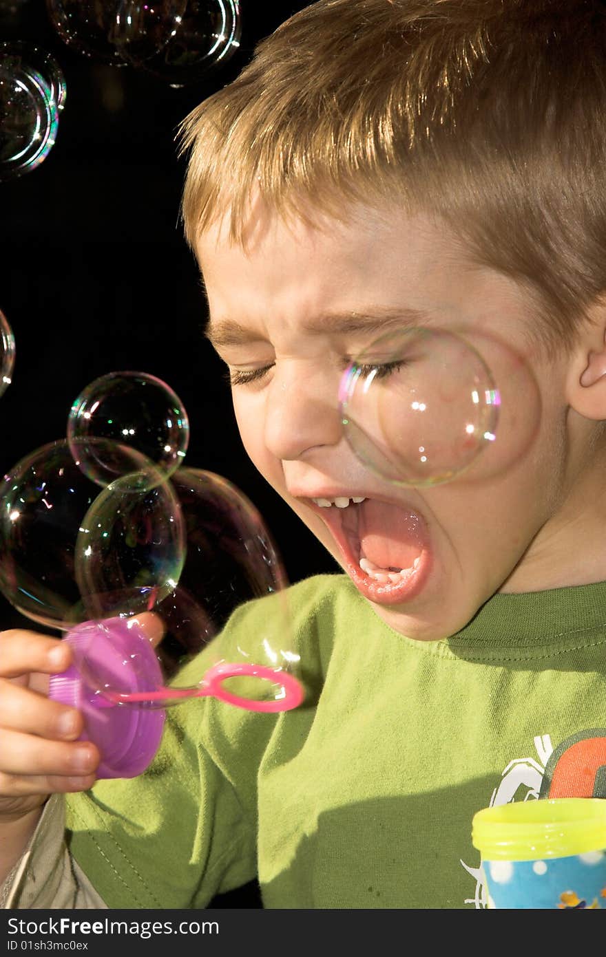 Young boy blowing bubbles outside in the sun