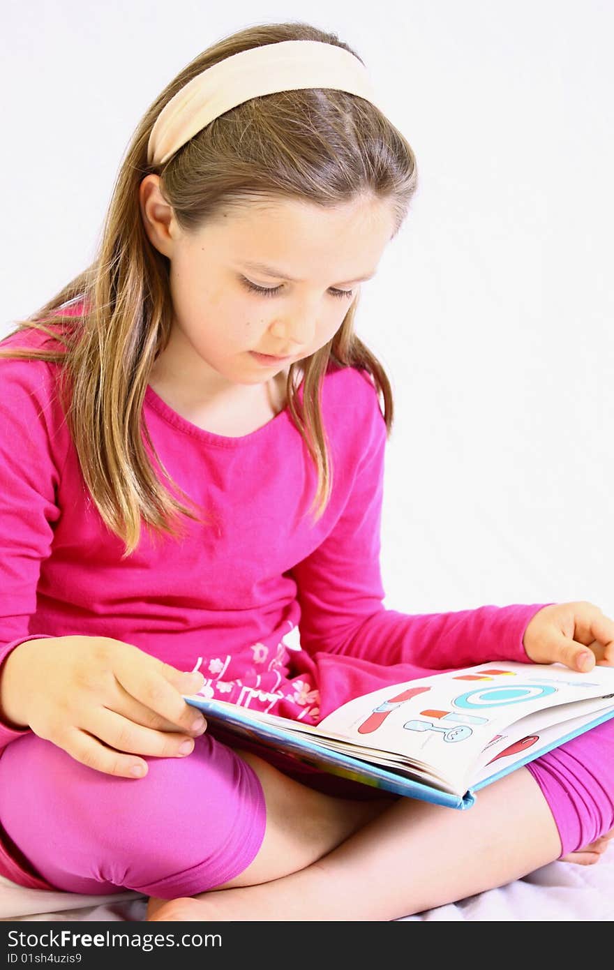 Young cute girl with pink dress reading book. Young cute girl with pink dress reading book.