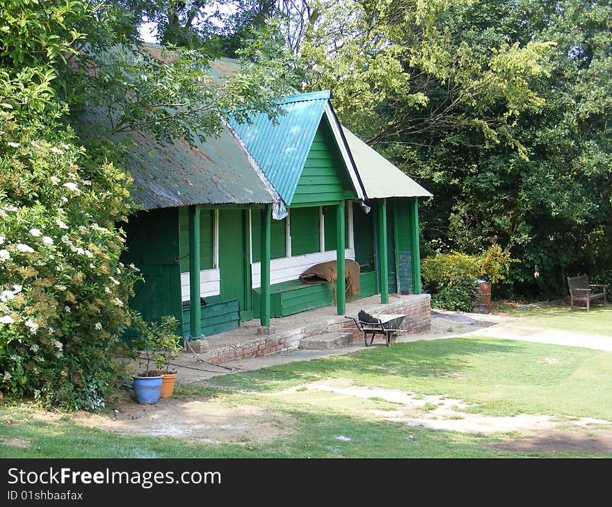 Abandoned green and white cricket pavillion and wheelbarrow. Abandoned green and white cricket pavillion and wheelbarrow