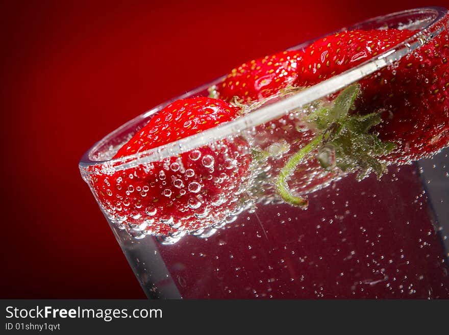 Three strawberry in a glass with water