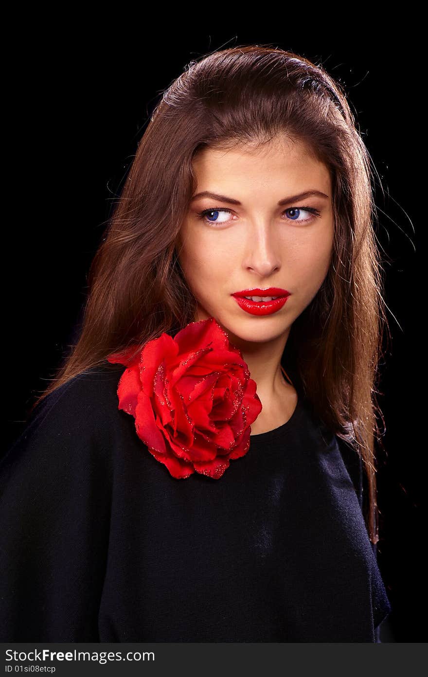 Portrait of a young beautiful brunettes with red lips in a black blouse decorated with a rose. Portrait of a young beautiful brunettes with red lips in a black blouse decorated with a rose