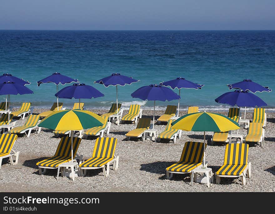 Beach with sun loungers and umbrellas near the blue sea. Beach with sun loungers and umbrellas near the blue sea