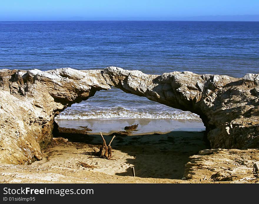 A rocked in the shape of a bridge near the beach. A rocked in the shape of a bridge near the beach