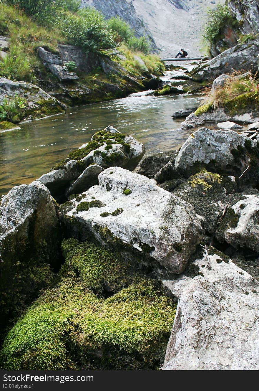 River with a bridge atop a sitting girl.