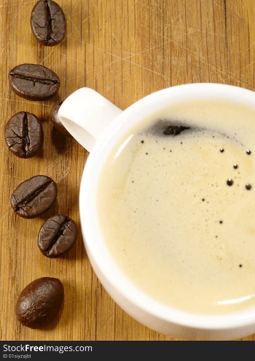 Cup of espresso with beans on the wooden desk