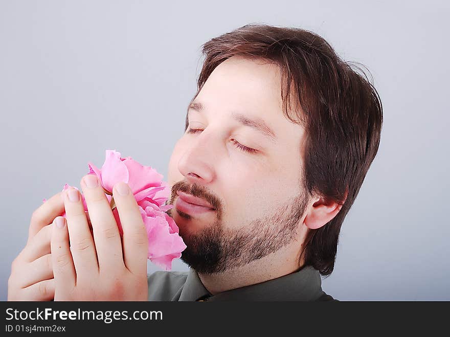 Cute man smeling pink roses and smiling