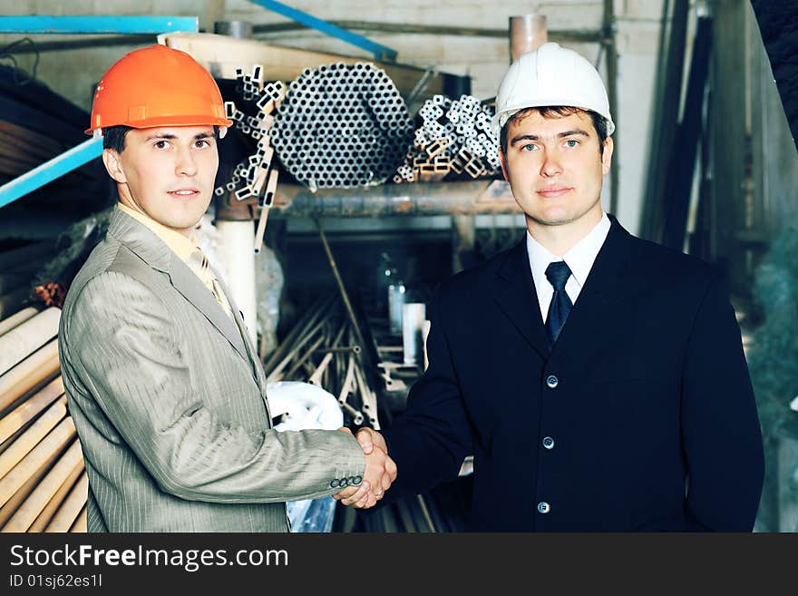 Industrial theme: two businessman shaking their hands at a manufacturing area. Industrial theme: two businessman shaking their hands at a manufacturing area.