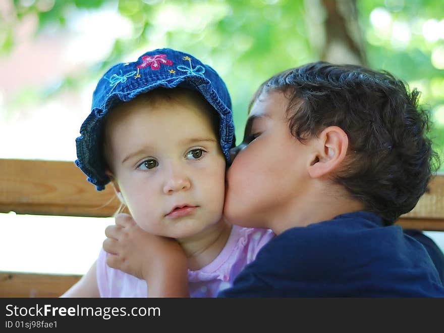 A little child is kissing small baby. A little child is kissing small baby